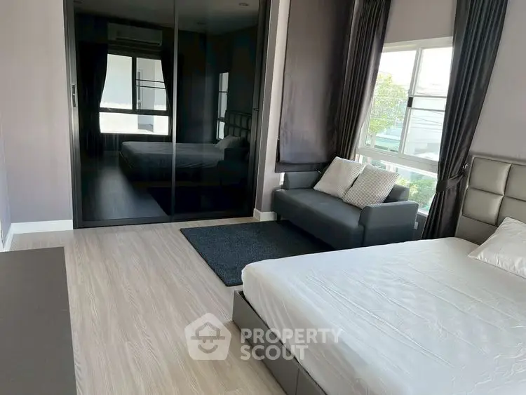 Modern bedroom with sleek design, featuring a large bed, sofa, and mirrored wardrobe.