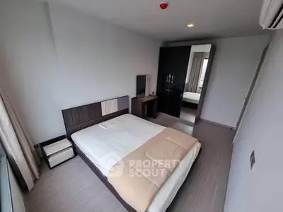 Modern bedroom with sleek design and ample natural light, featuring a stylish bed and wardrobe.