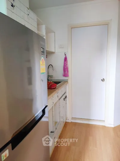 Compact kitchen with stainless steel fridge and wooden flooring