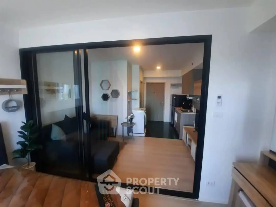 Modern open-plan apartment with glass partition, stylish decor, and compact kitchen.