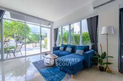 Bright living room with modern blue sofa and large windows overlooking garden