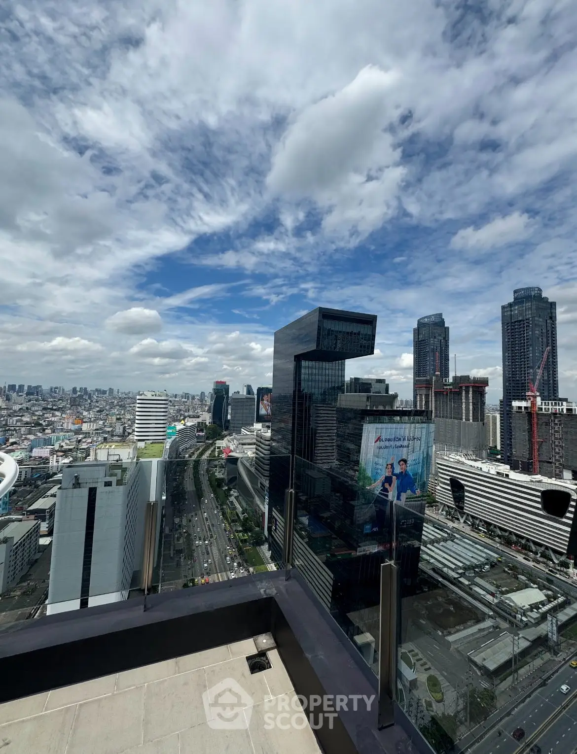 Stunning cityscape view from a high-rise balcony with modern skyscrapers and blue sky.