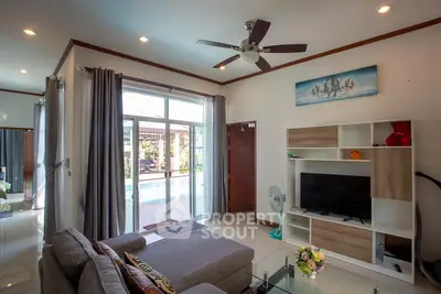 Spacious living room with modern decor and pool view, featuring a cozy sofa and entertainment unit.