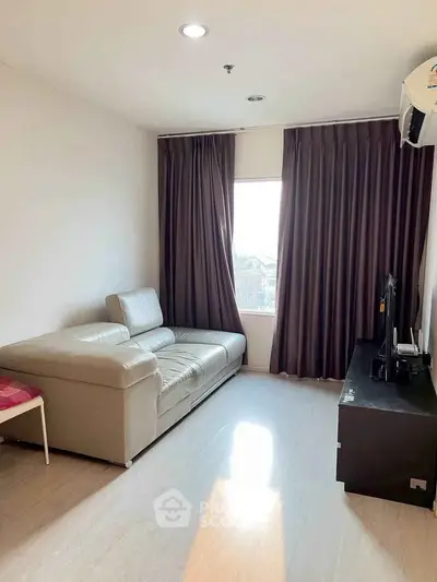 Cozy living room with modern sofa and entertainment unit, featuring natural light and elegant curtains.