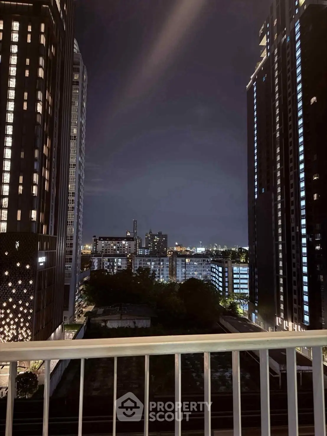 Stunning night cityscape view from a high-rise balcony, showcasing modern architecture and city lights.