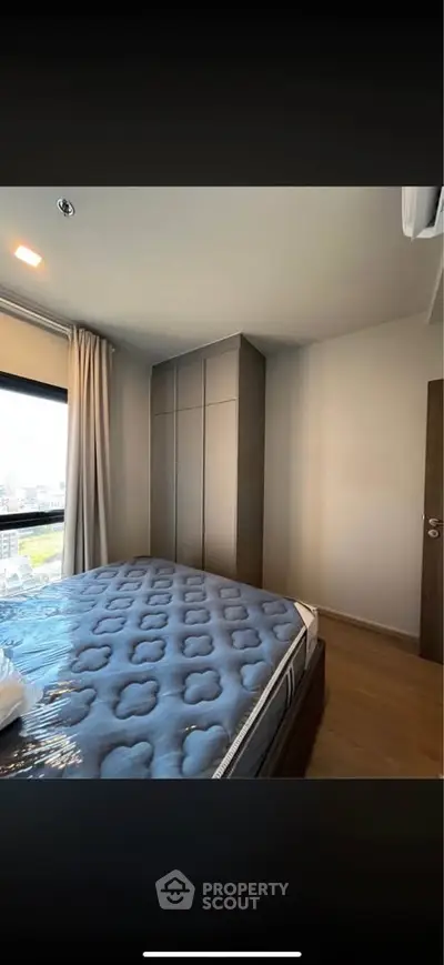 Modern bedroom with large window and stylish wardrobe in a high-rise apartment.