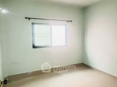 Spacious empty room with large window and neutral walls, perfect for customization.