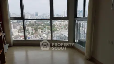 Spacious room with panoramic city view through large windows, perfect for urban living.
