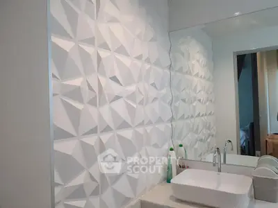 Modern bathroom with geometric wall tiles and sleek sink design