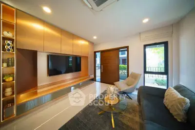 Modern living room with sleek design, featuring built-in TV unit, cozy seating, and large window for natural light.