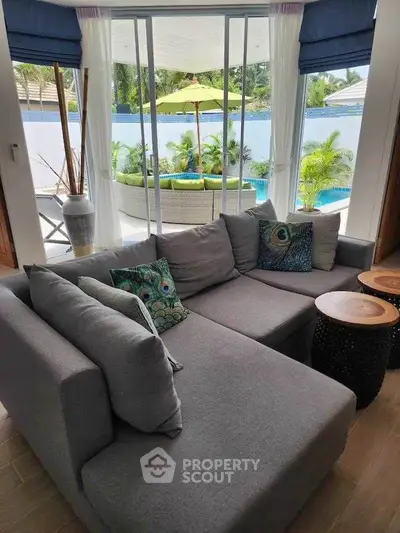 Luxurious living room with modern gray sofa and poolside view, perfect for relaxation and entertaining.