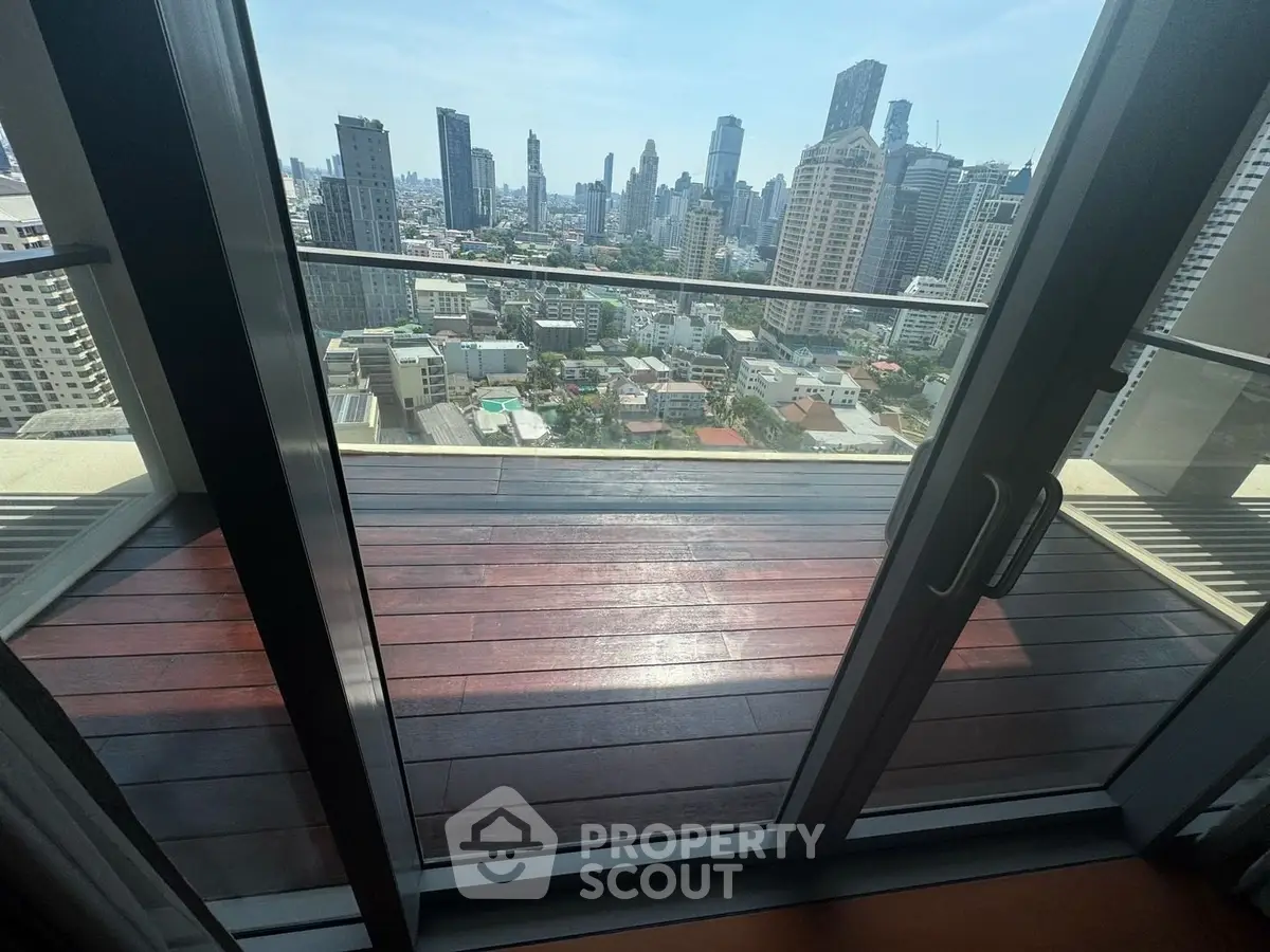 Stunning cityscape view from a high-rise balcony with sleek glass doors.