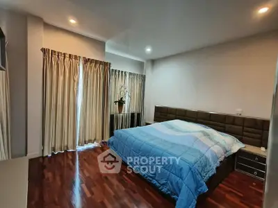 Spacious bedroom with elegant wooden flooring and cozy lighting