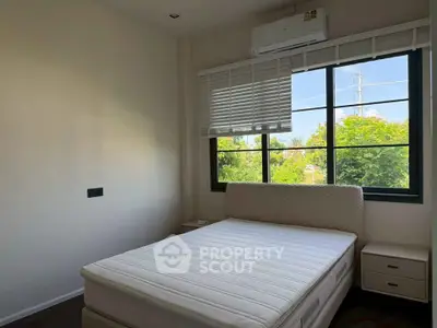 Bright bedroom with large window and air conditioning, featuring a comfortable bed and bedside tables.