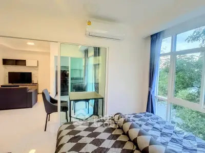 Modern bedroom with large windows and view into stylish living room