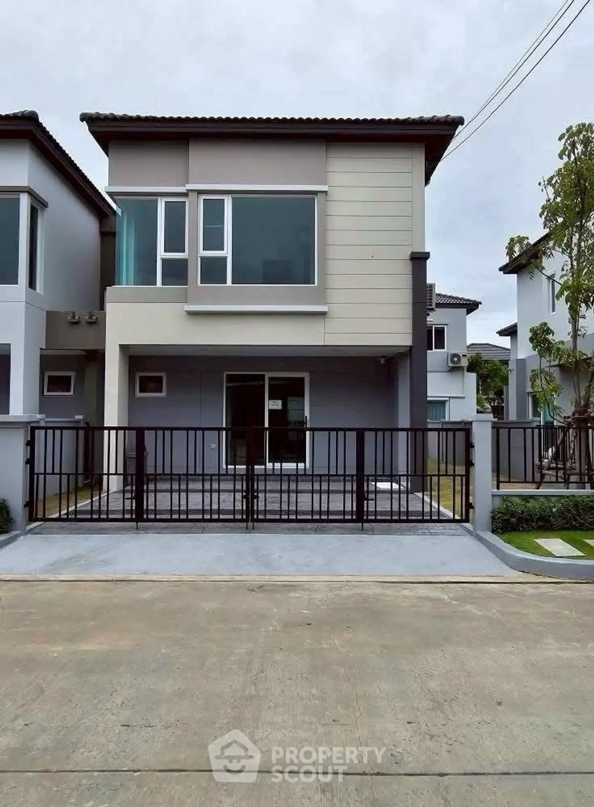 Modern two-story house with sleek design and gated driveway in a suburban neighborhood.