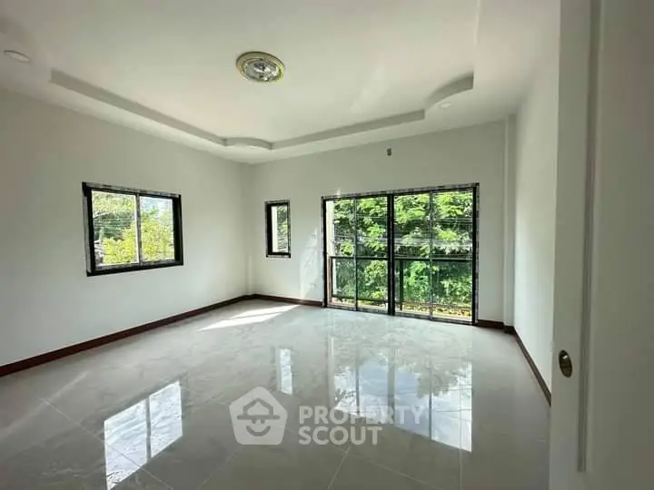 Spacious sunlit room with large windows and glossy tiled floor