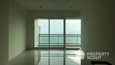 Spacious empty living room with large windows offering stunning ocean view.