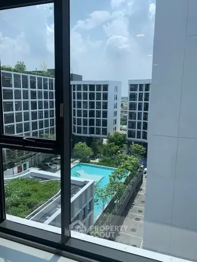 Modern apartment complex with pool view from window, showcasing urban living and luxury amenities.