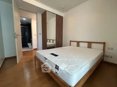 Spacious bedroom with wooden flooring and modern wardrobe in a stylish apartment.