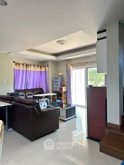 Spacious living room with modern decor and ample natural light, perfect for family gatherings.