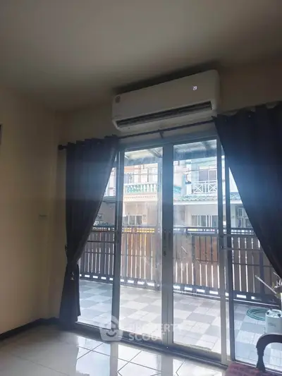 Spacious living room with sliding glass doors leading to a balcony, featuring an air conditioning unit.