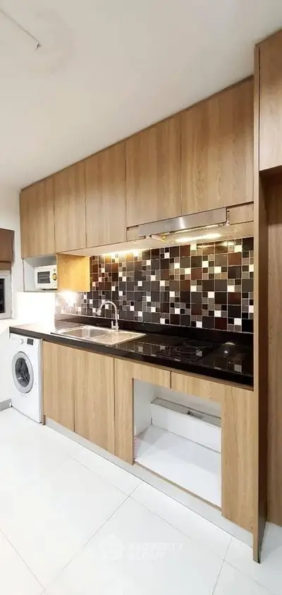 Modern kitchen with sleek wooden cabinets and stylish backsplash, featuring built-in appliances and washing machine.