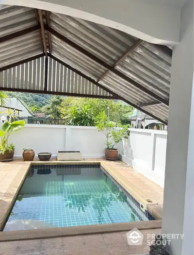 Charming private pool with tiled deck and lush greenery in serene outdoor setting.