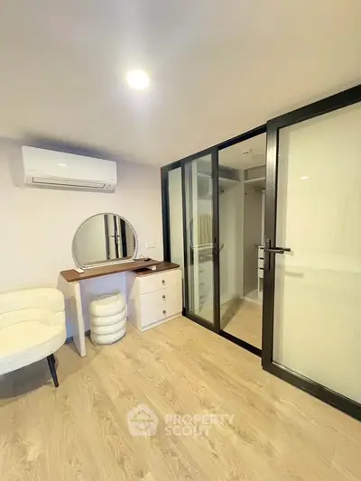 Modern bedroom with sliding glass closet doors and elegant vanity setup.