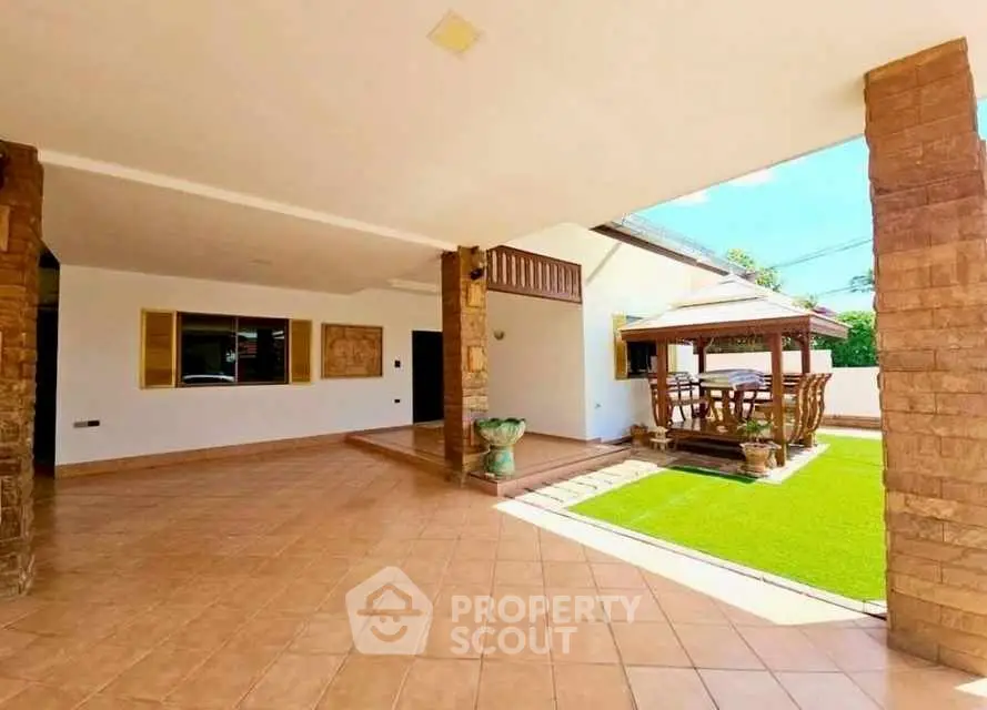Spacious outdoor patio with tiled flooring and garden seating area.