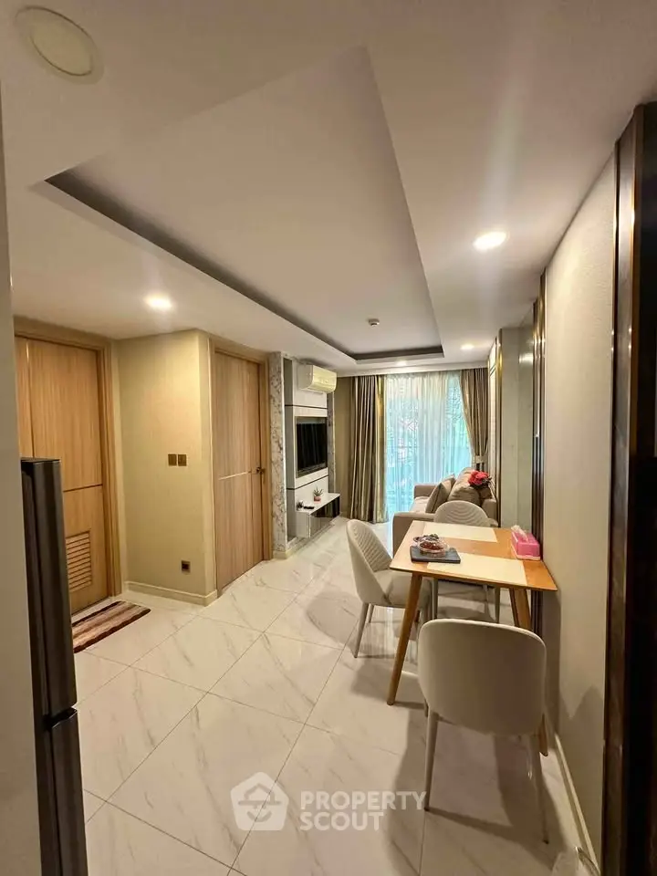 Modern living room with dining area, featuring elegant decor and natural light through large windows.