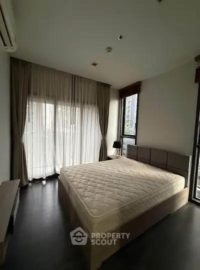 Spacious bedroom with large windows and modern decor in a luxury apartment.