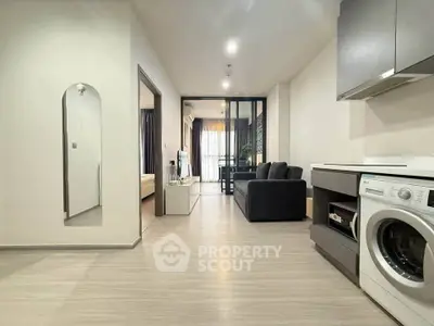Modern apartment interior with open layout, featuring a cozy living room and in-unit washing machine.