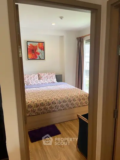 Cozy bedroom with floral bedding and natural light, perfect for relaxation.
