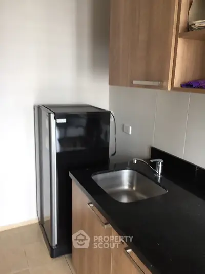 Modern kitchen with sleek black countertop and compact fridge