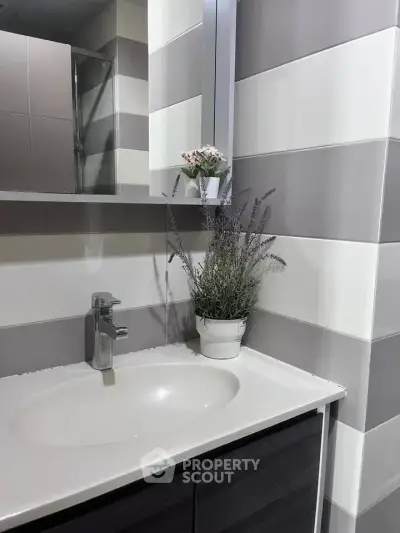 Modern bathroom with sleek sink and stylish gray tiles, featuring elegant floral decor.