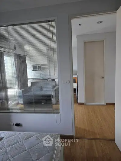 Modern apartment interior with wooden flooring and large windows for natural light.