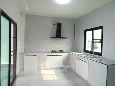 Modern kitchen with sleek design, featuring gas stove and ample natural light.