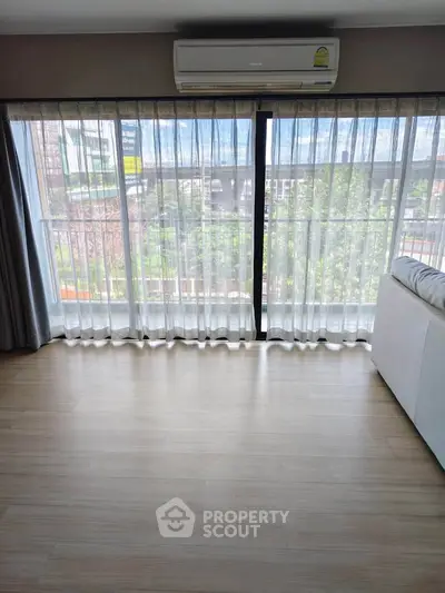 Spacious living room with large windows and air conditioning, perfect for natural light and comfort.