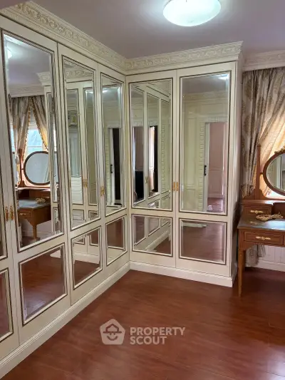 Elegant mirrored closet in luxurious bedroom with wooden flooring and classic vanity table.