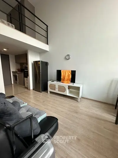Modern living room with loft, sleek furniture, and open kitchen layout in stylish apartment.