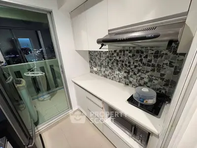 Modern kitchen with sleek cabinetry and balcony view, featuring a gas stove and stylish backsplash.