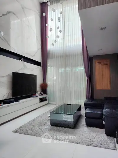Luxurious modern living room with high ceilings, elegant chandelier, and sleek marble accents.