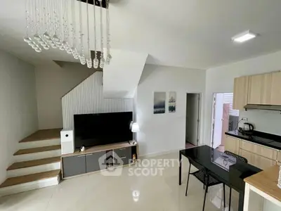 Modern open-plan living room with sleek kitchen and stylish staircase in a contemporary home.
