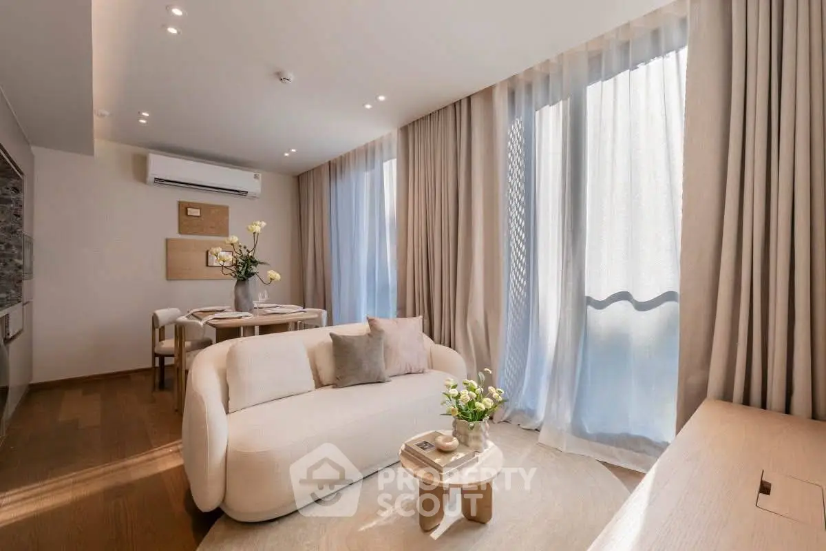 Elegant living room with modern furniture and large windows, featuring a cozy sofa and dining area.