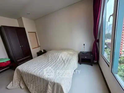 Cozy bedroom with large window and city view, featuring a comfortable bed and elegant decor.