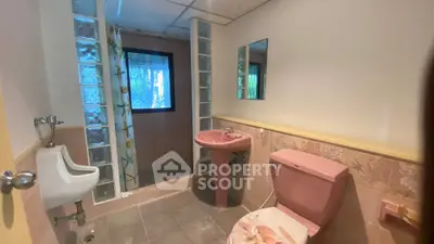 Charming vintage bathroom with pink fixtures and glass block shower in cozy home.