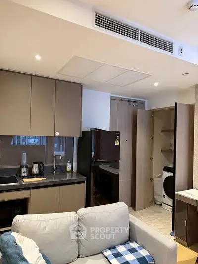 Modern kitchen with sleek cabinets and appliances, featuring a cozy living area with a sofa.