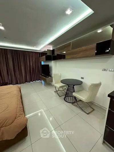 Modern bedroom with sleek furniture and ambient lighting, featuring a cozy seating area and stylish decor.