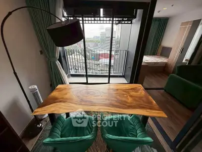 Modern apartment with stylish wooden table and green chairs, featuring a balcony with city view.